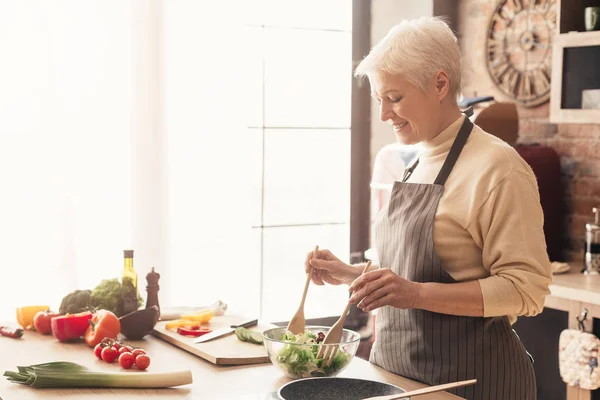 Seniorin kocht frischen Salat in Küche — Stockfoto