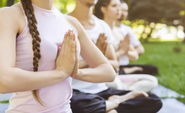 Primer plano de la gente haciendo gesto namaste en clase de yoga al aire libre — Foto de Stock