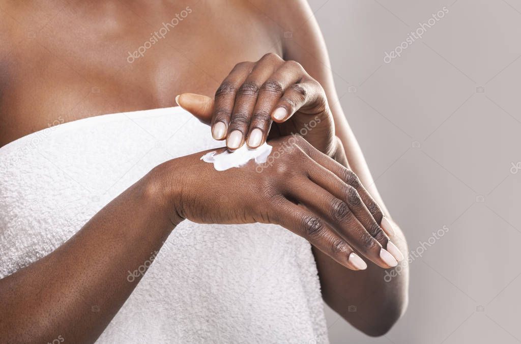 African girl applying body milk on her hand.