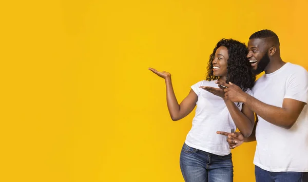 Homem e mulher afro-americanos apontam para um espaço vazio — Fotografia de Stock