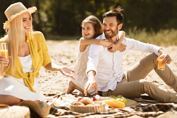 Счастливая молодая семья наслаждается пикником на природе — стоковое фото