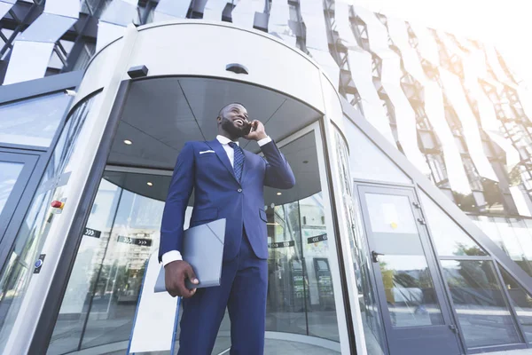 Afroamerikansk affärsman pratar på telefon mot modern kontorsbyggnad — Stockfoto