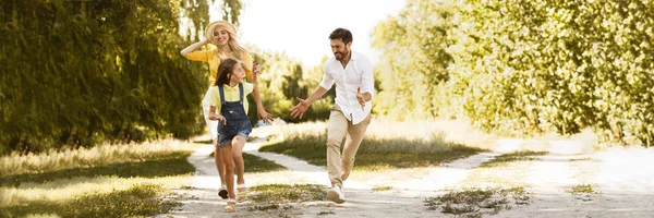 Menina feliz correndo de seus pais, fazendo piquenique no campo — Fotografia de Stock