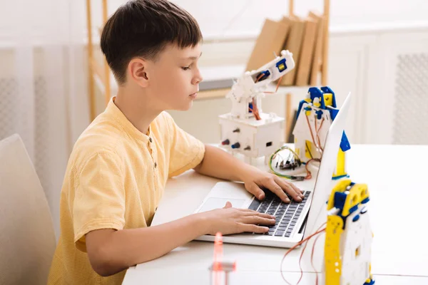 Boy creating robotics project on laptop in class