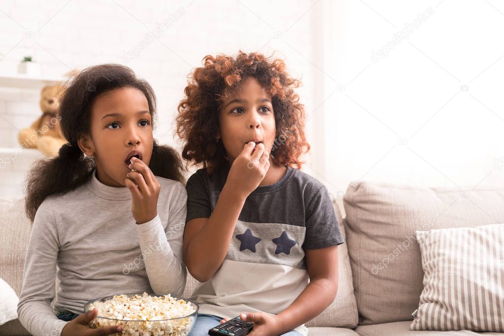 Interested girls watching discovery film and eating popcorn