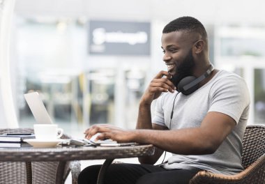 Yakışıklı Afrikalı adam kafede ücretsiz wifi ile dizüstü bilgisayar ını kullanarak