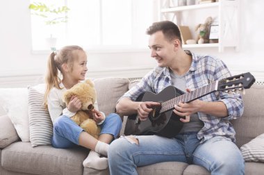 Sevimli küçük kız ve onun yakışıklı babası gitar çalıyor