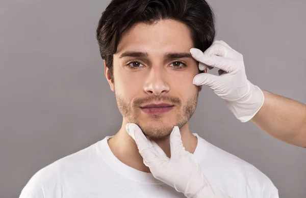 Esteticista masaje su cara de joven guapo hombre — Foto de Stock