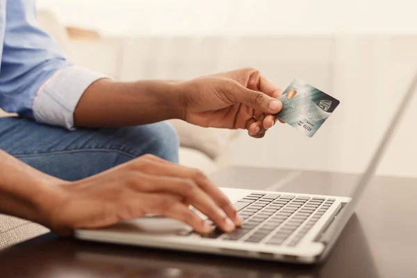 Hombre negro ingresando información desde la tarjeta de crédito utilizando el ordenador portátil —  Fotos de Stock