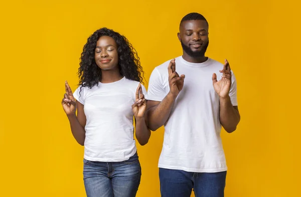 African American par stängning ögon och korsar fingrar med hopp — Stockfoto