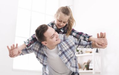 Neşeli baba kızını sırtında tutuyor.