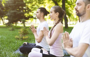 Açık havada yoga yaparken namaste el ele tutuşan üç arkadaş