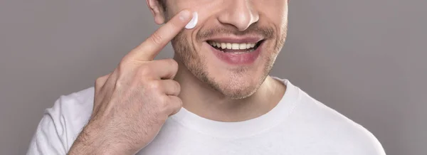 Homem sorridente rosto hidratante com crea,. close up retrato — Fotografia de Stock