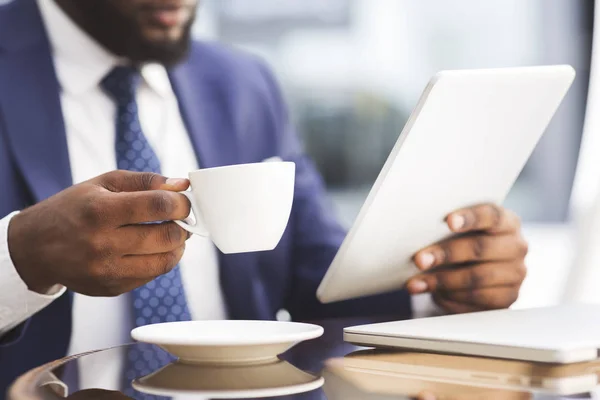 Nierozpoznawalny African American biznesmen o kawę podczas pracy na tablecie — Zdjęcie stockowe