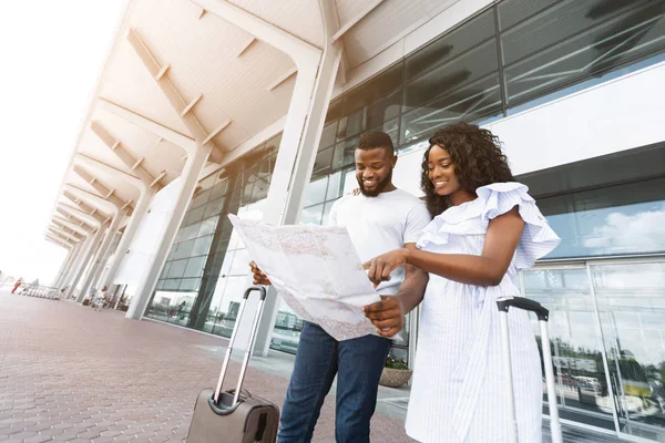 Pareja negra joven mirando el mapa en el edificio de la terminal del aeropuerto — Foto de Stock