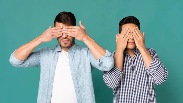 Dos hombres cubriendo sus ojos con las manos sobre fondo turquesa — Foto de Stock