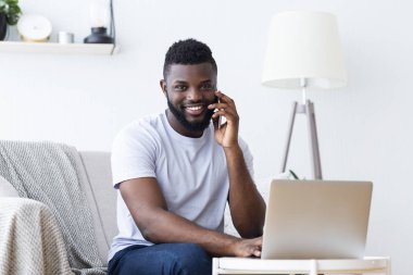 Siyah adam laptop ve arama üzerinde çalışıyor