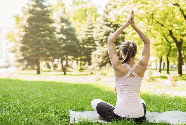 Mujer joven sentada en posición de loto disfrutando meditando al aire libre — Foto de Stock