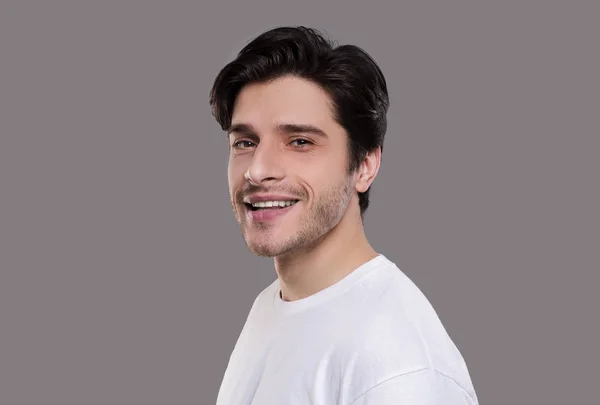 Positiver gutaussehender Mann lächelt auf grauem Hintergrund — Stockfoto