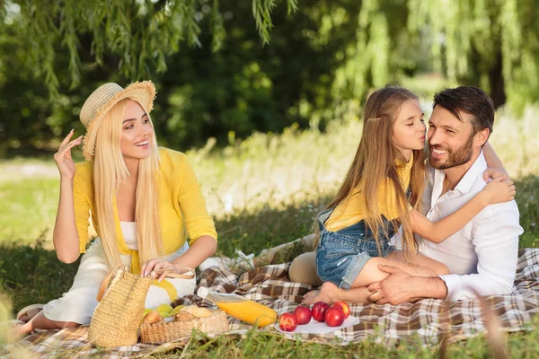 Um piquenique familiar. Filha beijando pai na bochecha — Fotografia de Stock