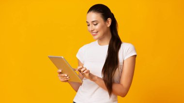 Sarı Arka Planda Tablet Bilgisayar Kullanan Gülümseyen Kız