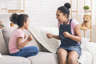 Furious african sisters screaming at each other on couch clipart