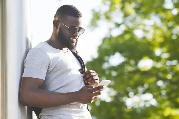 Hombre africano alegre con mochila hablando en línea por teléfono — Foto de Stock