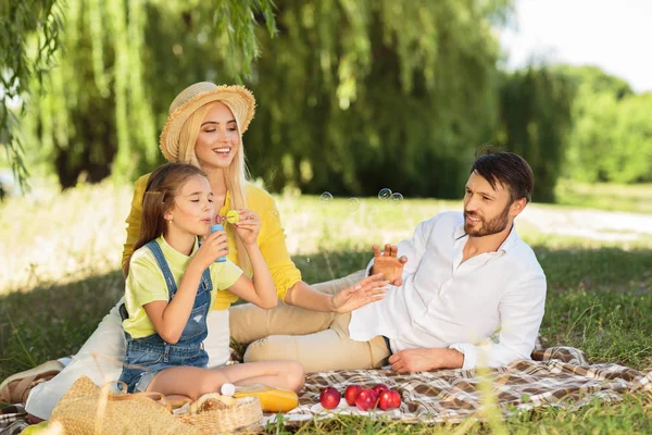 Lycklig familj blåser bubblor i sommarpark — Stockfoto
