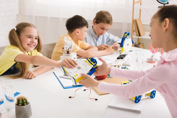 Girl giving robot model to friend at STEM lesson — Stock Photo, Image