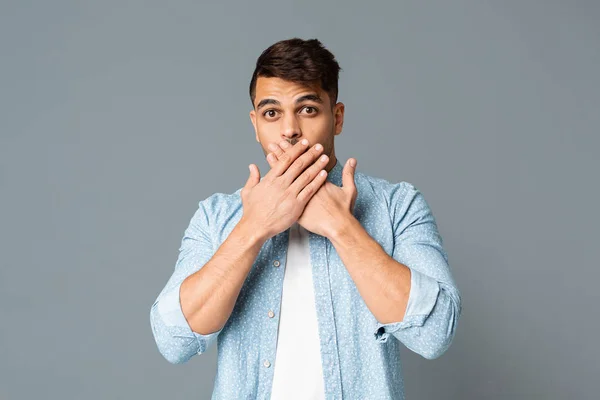 Shocked guy covering his mouth with hands on gray background. — Stock Photo, Image
