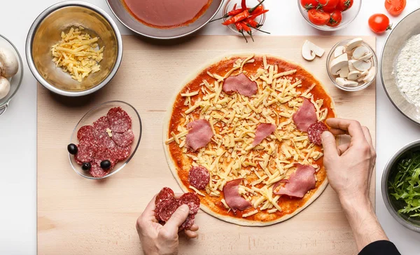 Chef dekoriert italienische Pizza mit Schinken und Salamischeiben — Stockfoto