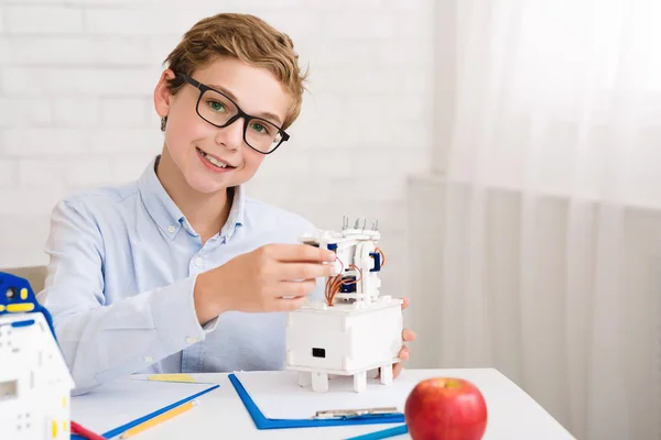 Niño feliz construyendo robot eléctrico y mirando a la cámara —  Fotos de Stock