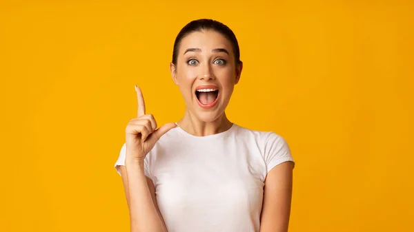 Millennial chica señalando dedo hacia arriba en amarillo fondo —  Fotos de Stock