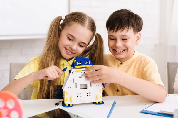 Enfants heureux construisant un jouet robotique à la classe de tige — Photo