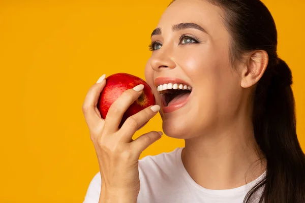 Menina com sorriso branco perfeito segurando maçã em fundo amarelo — Fotografia de Stock