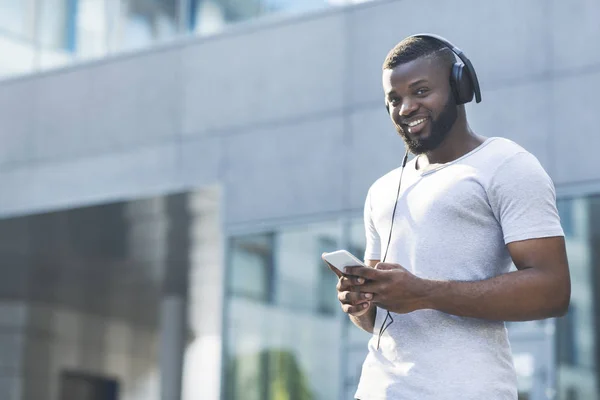 屋外の携帯電話でヘッドフォンでアフリカの男性の肖像画 — ストック写真