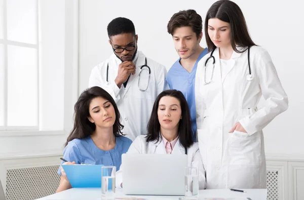 Multirasistiska läkare som tittar på laptop, arbetar tillsammans i kliniken — Stockfoto