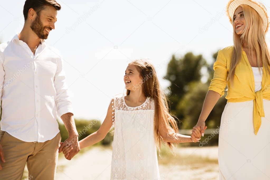 Parents and child walking, holding hands outdoors