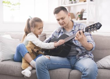 Sevimli küçük kız gitar çalmak için babası na yardım ediyor
