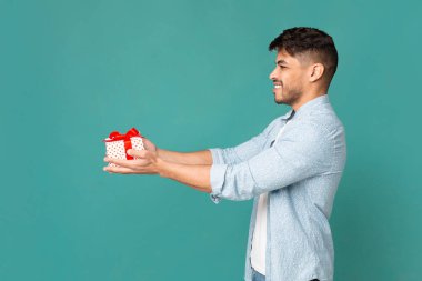 Arap adam kırmızı kurdele ve yay ile hediye kutusu tutan