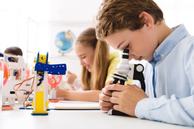 Çocuk robot ile mikroskop bakarak yakın