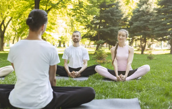 Yoga iniciantes ouvindo instrutor sentado em pose de lótus — Fotografia de Stock