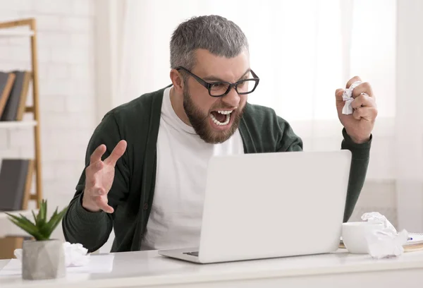 Злой бородатый мужчина кричит на свой ноутбук — стоковое фото