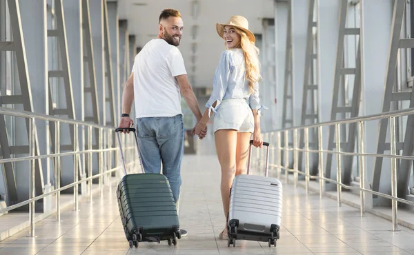 Pareja joven que lleva equipaje en la terminal del aeropuerto — Foto de Stock