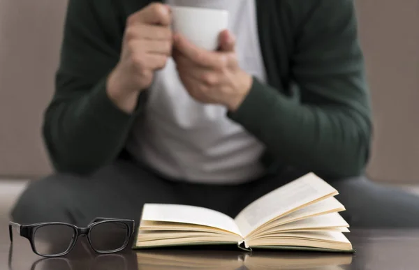 Caucásico hombre leyendo libro y beber café en casa —  Fotos de Stock