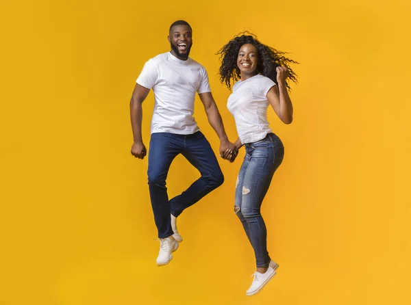 Encantador casal afro está pulando de mãos dadas — Fotografia de Stock