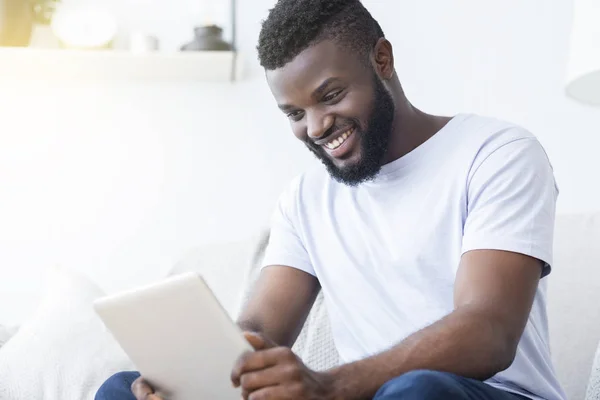 Afro-americano hombre viendo película en tableta en el interior —  Fotos de Stock