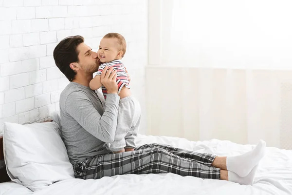 Pai feliz passar o tempo com o bebê, beijando o filho em casa — Fotografia de Stock