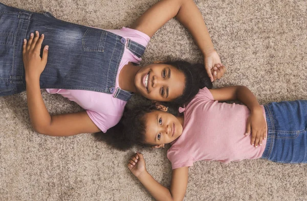Adolescente y poco afroamericano niñas acostadas juntas en el suelo — Foto de Stock