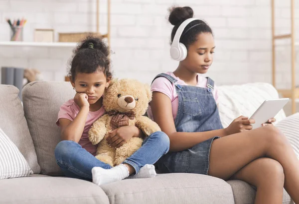 Little african girl boring alone, her elder sister watching videos — Stock Image Little african girl boring alone, her elder sister watching videos Royalty Free Stock Photos